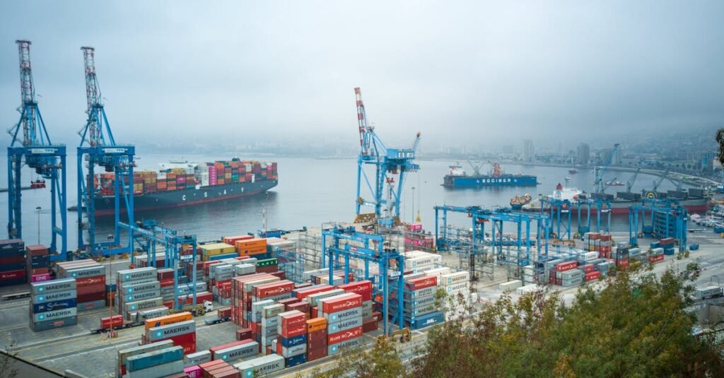 Aerial view of bustling Valparaíso port with container ships and cranes on a foggy day.