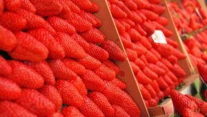 Bright red strawberries neatly stacked, showcasing vibrant color and freshness at a market stall.